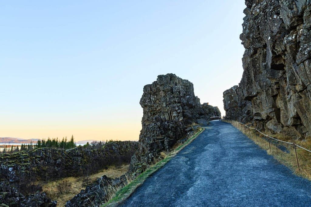 Asphaltierter Wanderweg zwischen hohen, zerklüfteten Felswänden bei warmem Seitenlicht