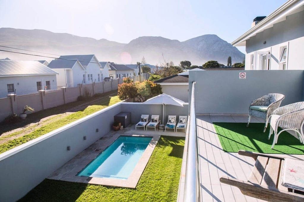 Blick von Balkon auf kleinen Pool im Garten mit Liegen und Bergen im Hintergrund