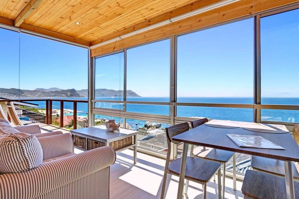 Helles Wohnzimmer mit großen Fenstern und weitem Meerblick, Holzdecke und Balkon