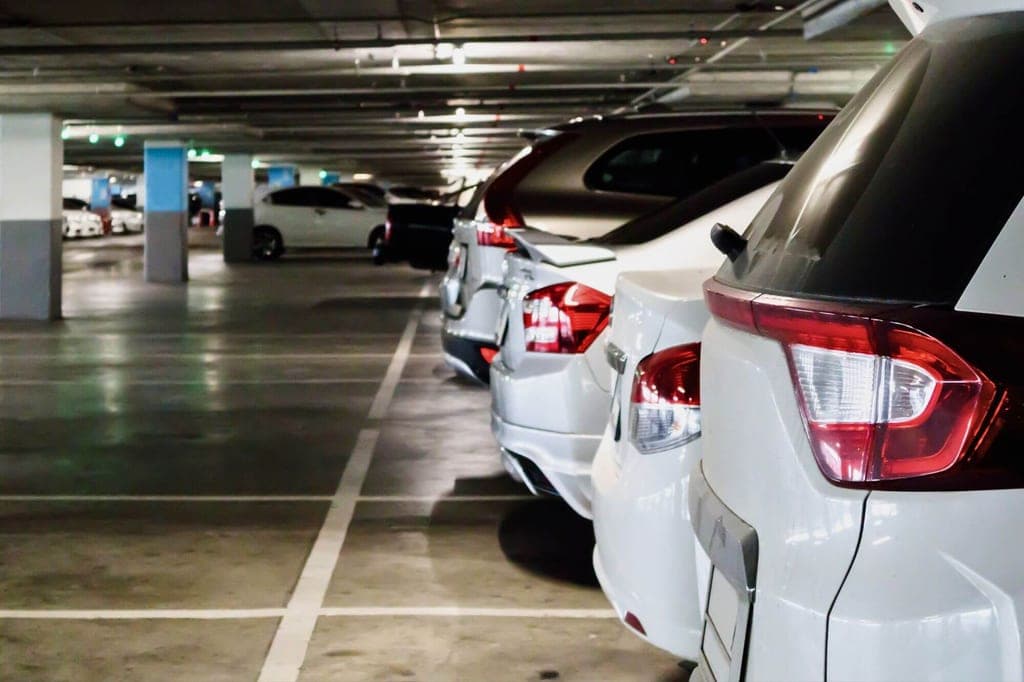 Innenaufnahme einer Tiefgarage mit einer Reihe geparkter Autos, Fokus auf den Heckbereich mehrerer Fahrzeuge.