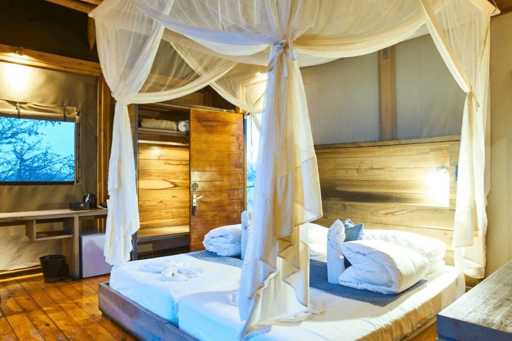 Gemütliches Schlafzimmer mit Himmelbett, Moskitonetz, Holzfußboden und warmem Abendlicht