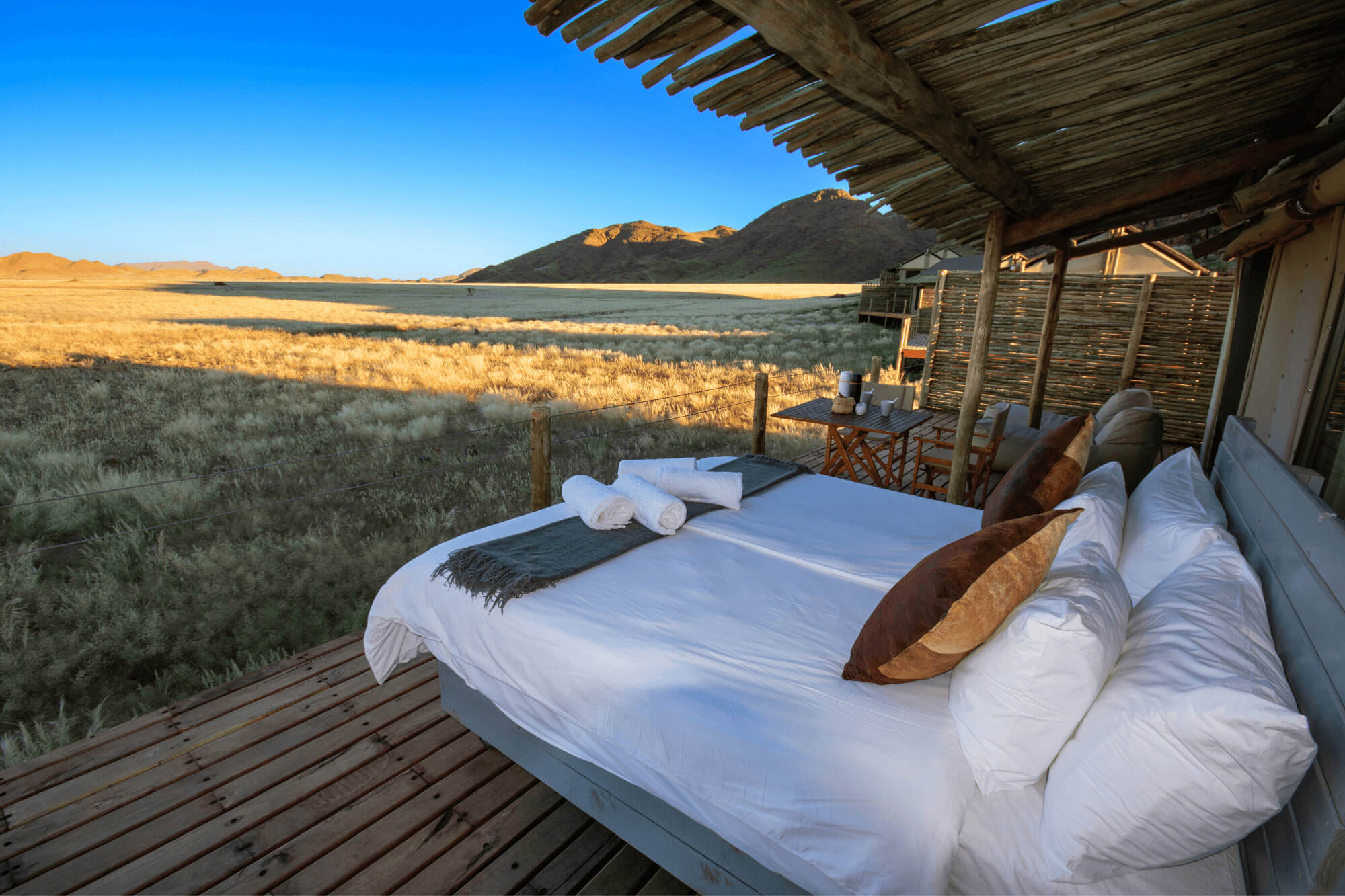 Ein Doppelbett steht auf der Terrasse im Elegant Desert Camp