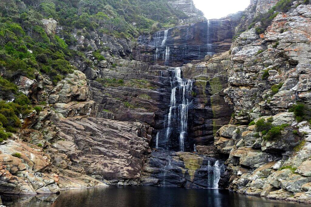 Wandere zum Küstenwasserfall entlang von Felsen, Gischt und Meer